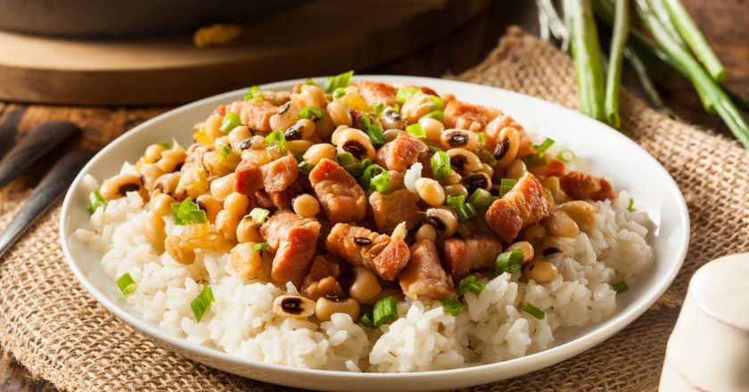 Pinto Beans and rice with bacon on a white plate on top of a table