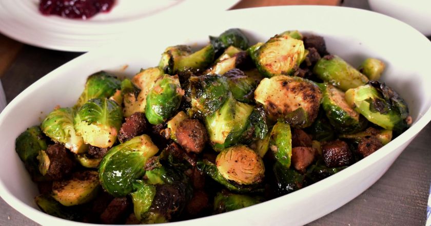 a white serving dish filled with roasted Brussels sprouts