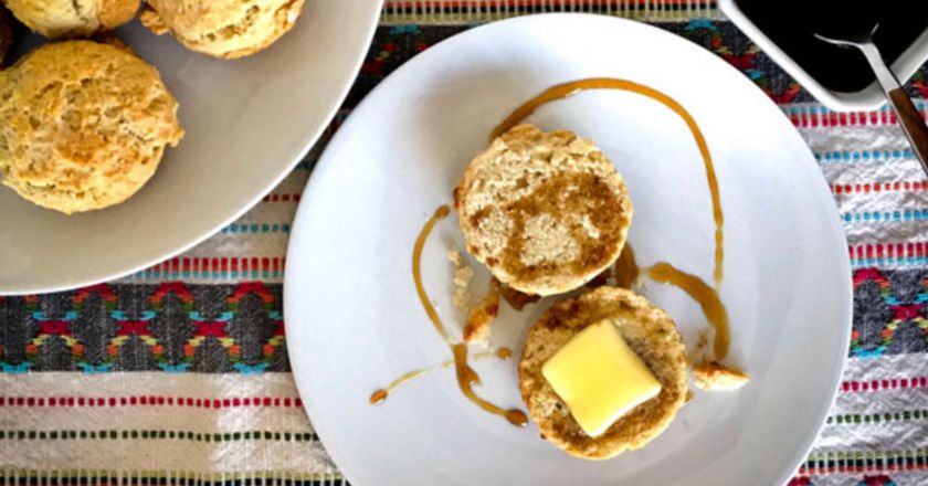 a biscuit sliced in half on a white place with a bigger plate of biscuits next to it