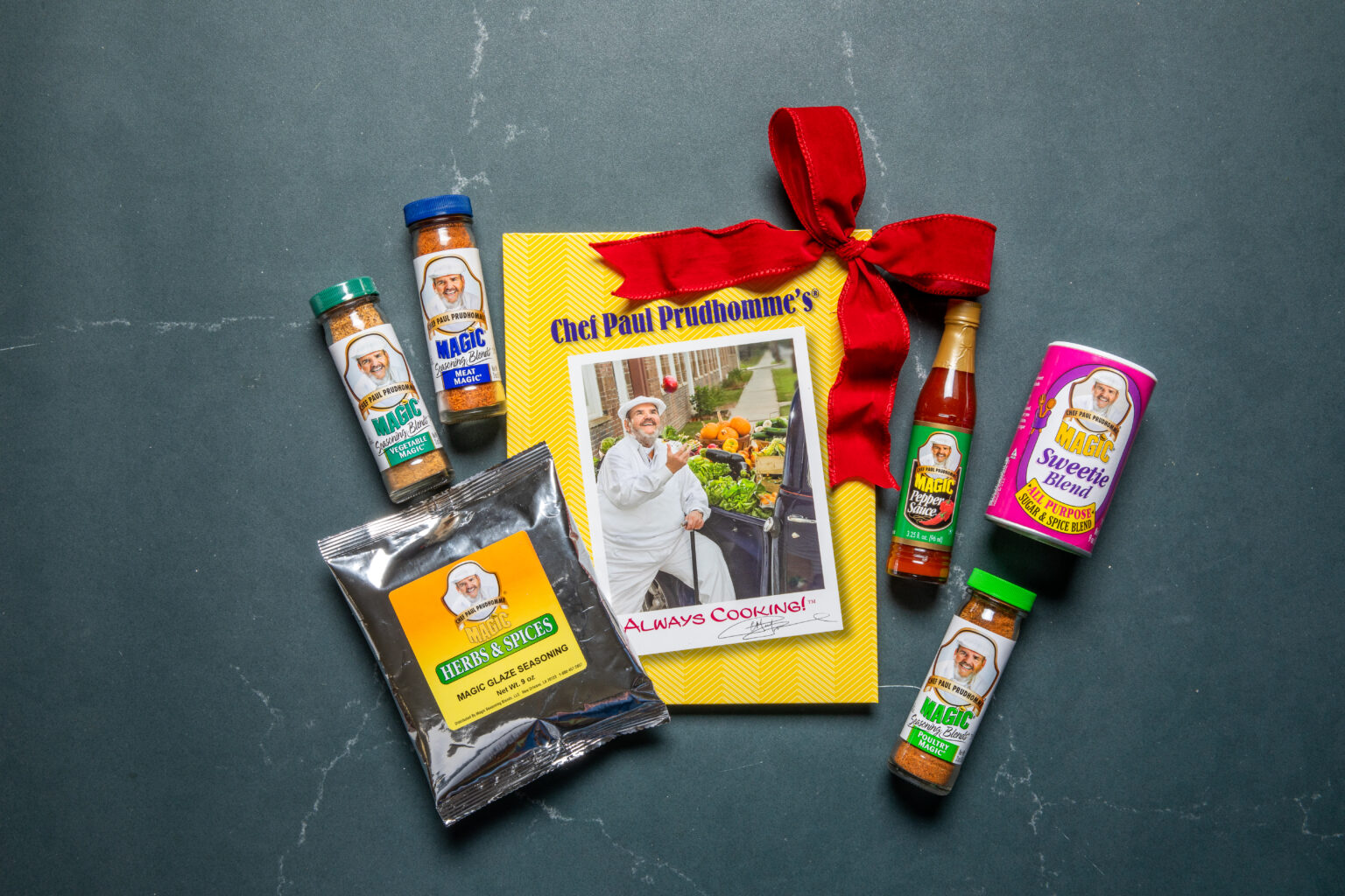 the feast and flavor holiday bundle featuring Chef Paul's Always Cooking cookbook, a bottle of his magic pepper sauce, a bottle of poultry magic, a bottle of vegetable magic, a bottle of meat magic, a canister of his sweetie magic and a silver pouch of magic glaze