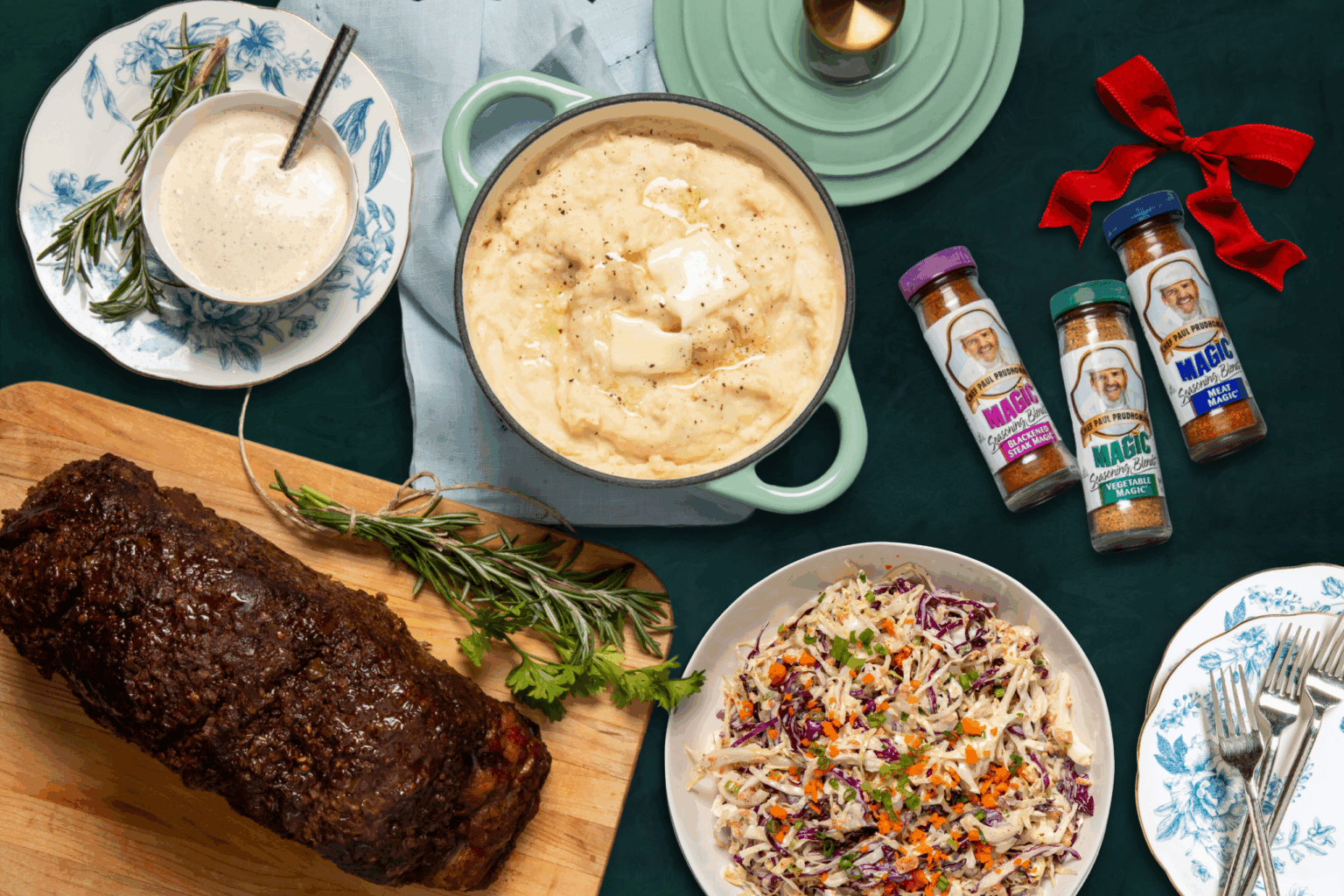 Roast beef, mashed potatoes and coleslaw on top of a table in different serving dishes, with several bottles of magic seasonings
