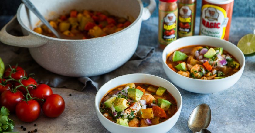 two bowls of soup next to a large pot of soup and tomatoes