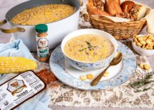 Slow Cooker Corn Chowder in a bowl with tasso and corn, alongside Vegetable Magic seasoning.