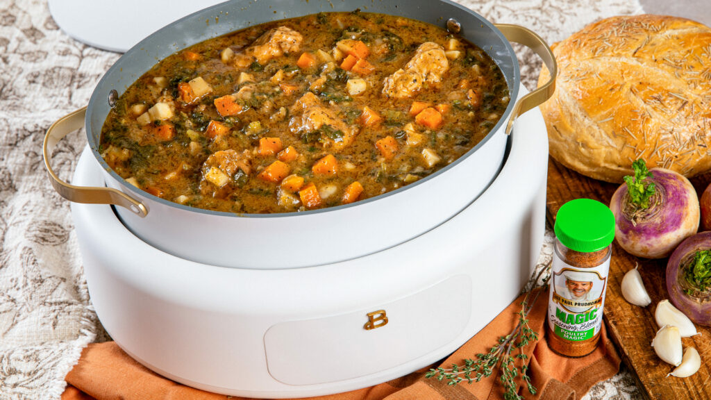 Turkey and fall vegetable stew in a crockpot and bowl, with a bowl of wild rice, sliced rosemary bread, and a bottle of Chef Paul Prudhomme’s Poultry Magic.